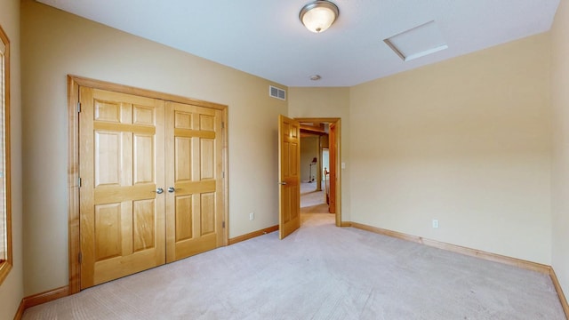 unfurnished bedroom featuring light carpet, attic access, visible vents, and baseboards