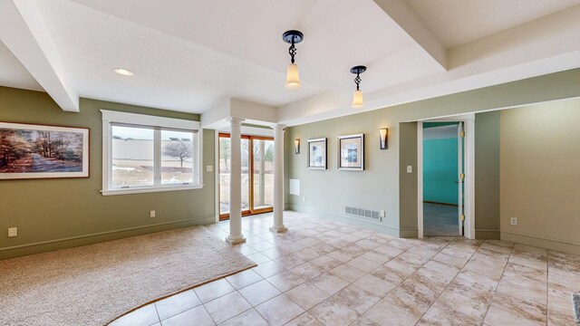 carpeted empty room featuring baseboards, decorative columns, visible vents, and beam ceiling