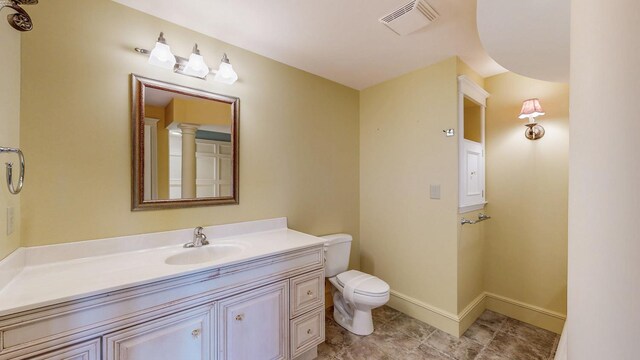 bathroom featuring visible vents, toilet, vanity, baseboards, and tile patterned floors