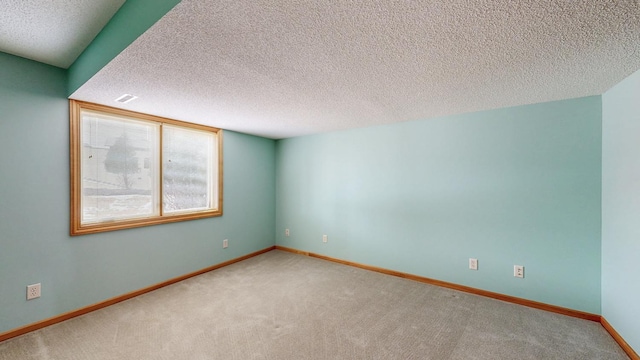 carpeted empty room featuring visible vents, a textured ceiling, and baseboards