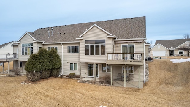 rear view of property featuring roof with shingles, a yard, central air condition unit, a patio area, and a wooden deck