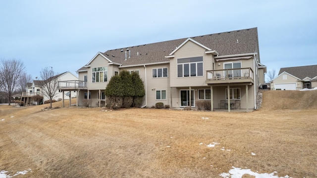 back of property with a shingled roof and a wooden deck