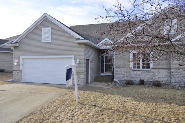 view of front of home featuring concrete driveway, stone siding, a front yard, and roof with shingles