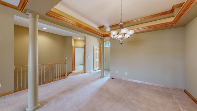 empty room with a chandelier, a tray ceiling, light colored carpet, and ornate columns