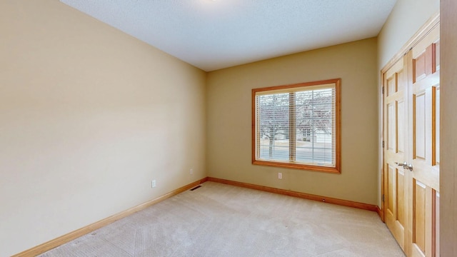 spare room with baseboards, light carpet, and visible vents