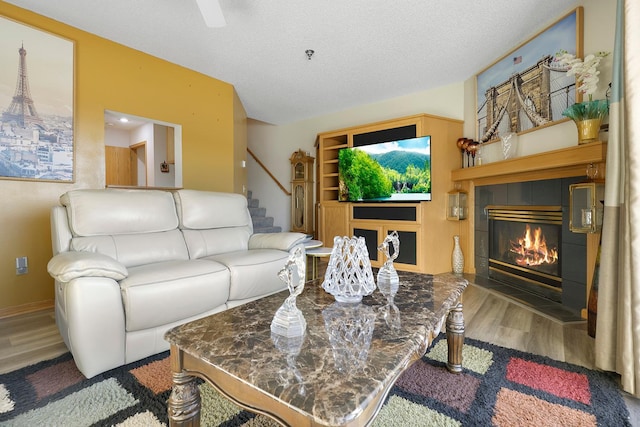 living area with a textured ceiling, a fireplace, wood finished floors, and stairs