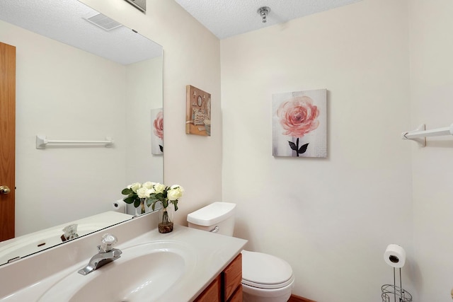 bathroom featuring visible vents, vanity, toilet, and a textured ceiling