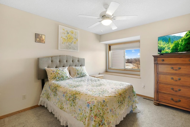 bedroom with light carpet, ceiling fan, a textured ceiling, and baseboards