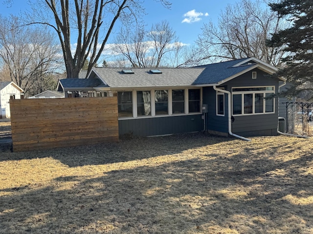 back of house featuring roof with shingles and fence