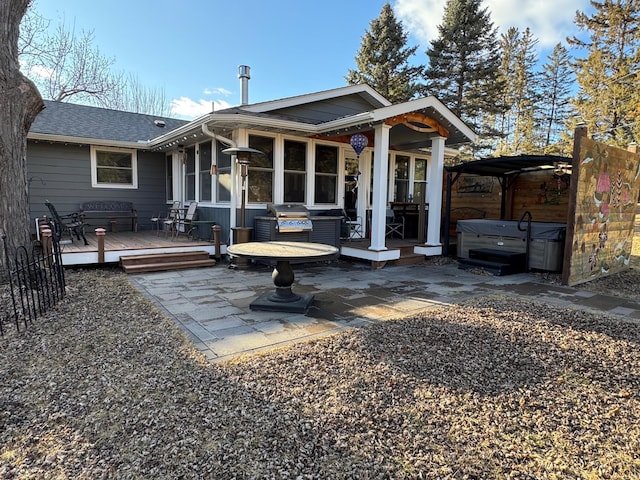 back of house featuring a shingled roof, a wooden deck, and a sunroom