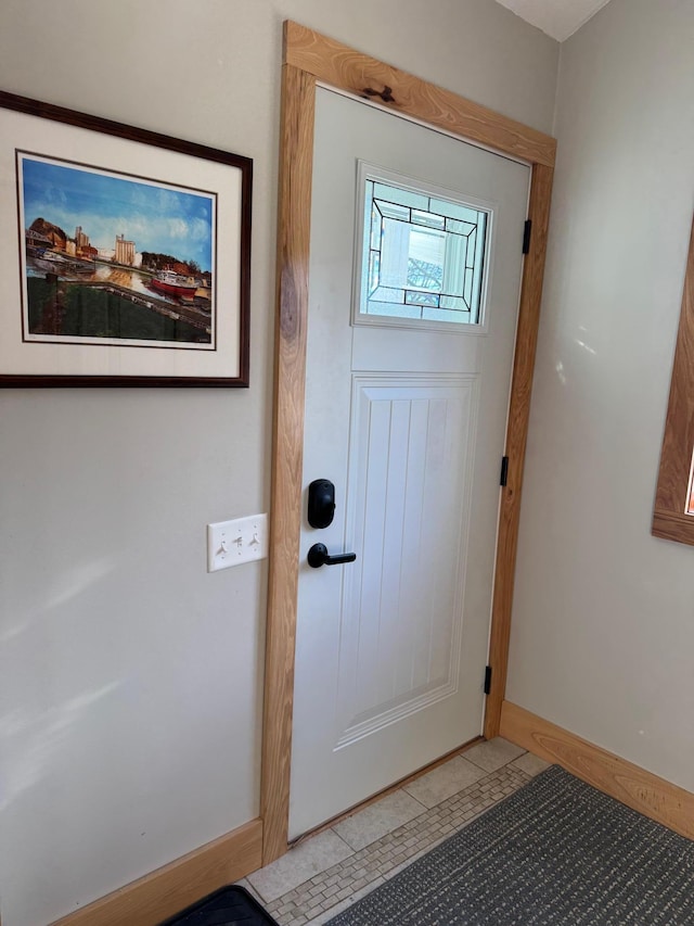 doorway featuring light tile patterned flooring and baseboards