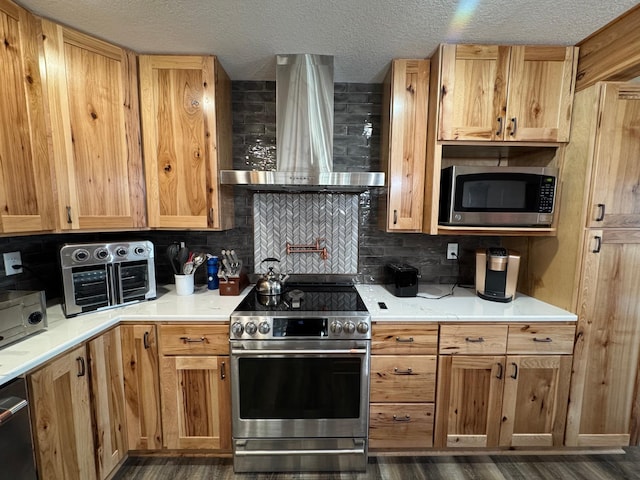 kitchen with wall chimney range hood, stainless steel appliances, backsplash, and light countertops