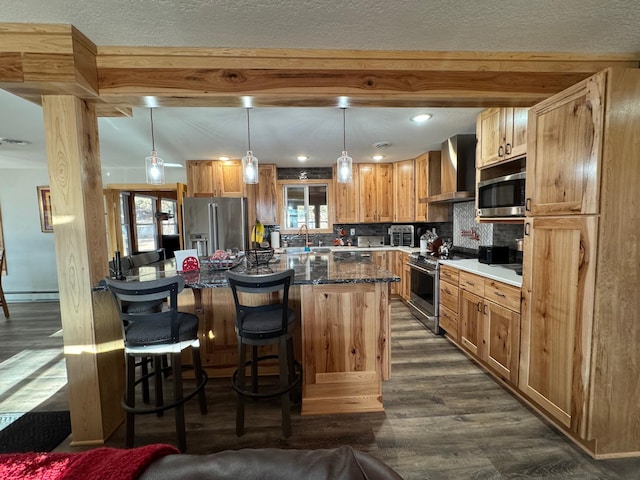 kitchen with stainless steel appliances, wall chimney range hood, dark wood-type flooring, and beam ceiling