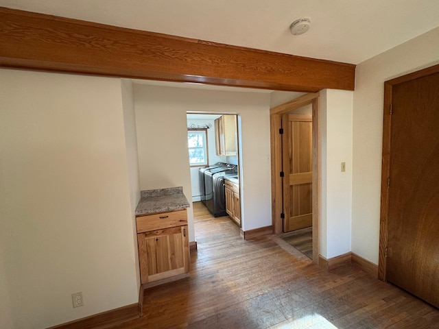 corridor featuring separate washer and dryer, beam ceiling, hardwood / wood-style flooring, and baseboards