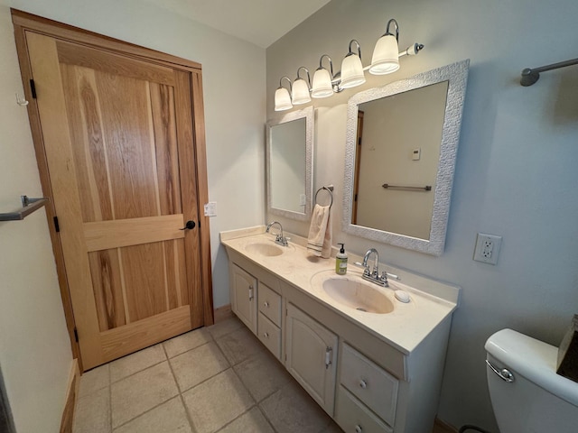 full bathroom featuring toilet, double vanity, a sink, and tile patterned floors