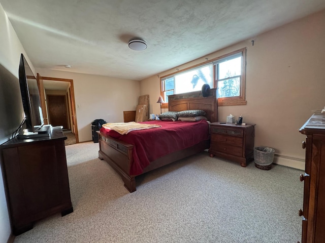 bedroom with baseboards, a baseboard heating unit, a textured ceiling, and light colored carpet