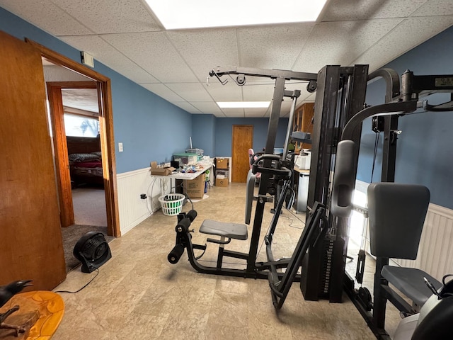 workout area with a wainscoted wall and a drop ceiling