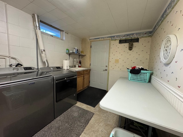 laundry area featuring wallpapered walls, cabinet space, wainscoting, washer and dryer, and a sink