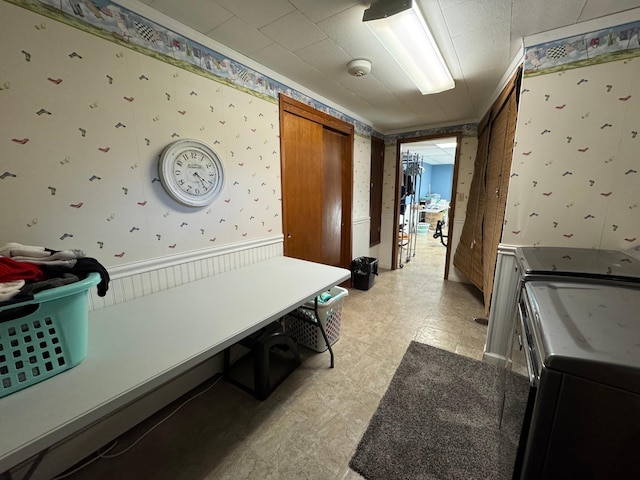 laundry area with washer and clothes dryer, light floors, wainscoting, laundry area, and wallpapered walls