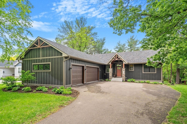 view of front of house featuring aphalt driveway, a garage, a shingled roof, a front lawn, and board and batten siding