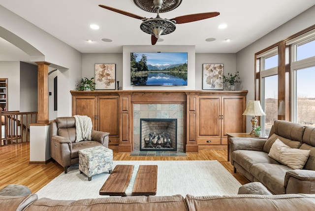 living area featuring light wood finished floors, a tiled fireplace, decorative columns, and recessed lighting