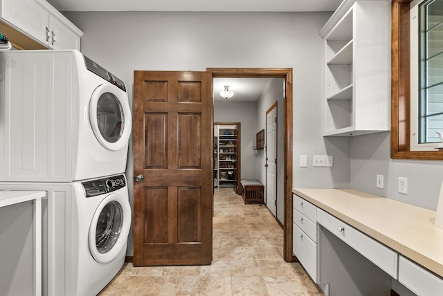 washroom with cabinet space and stacked washer / drying machine