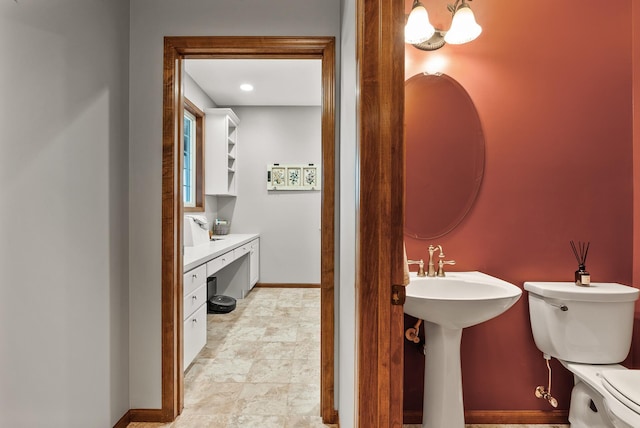 half bathroom featuring a sink, toilet, and baseboards