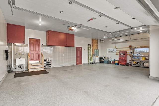 garage featuring a garage door opener, electric panel, and a sink