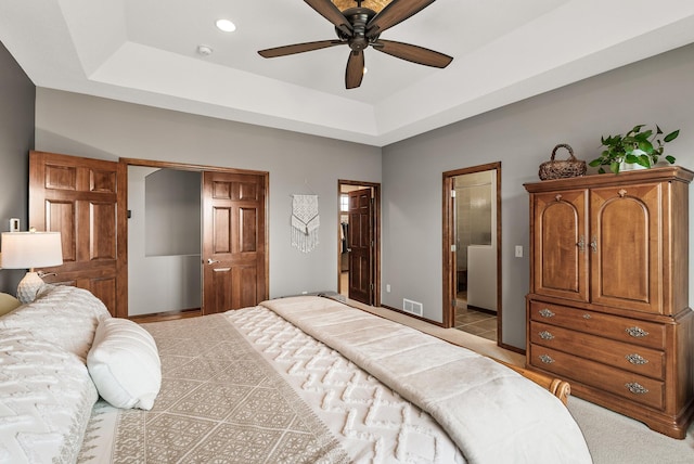 bedroom with ensuite bathroom, recessed lighting, visible vents, baseboards, and a raised ceiling