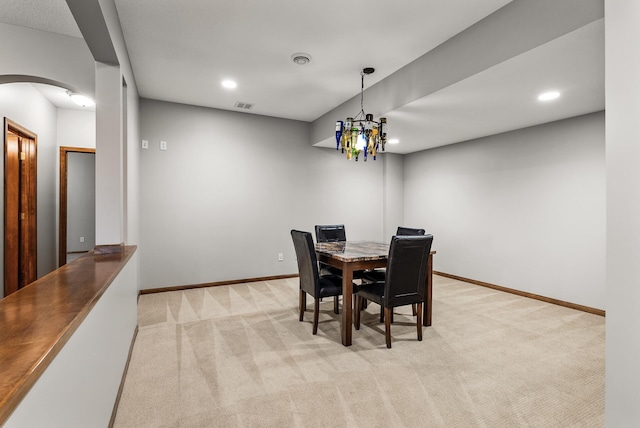 dining room featuring arched walkways, baseboards, visible vents, and light colored carpet