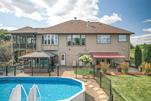 view of swimming pool featuring a fenced in pool, a sunroom, a gazebo, a yard, and a patio area