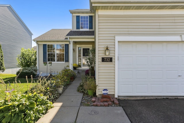 property entrance featuring a garage and a shingled roof