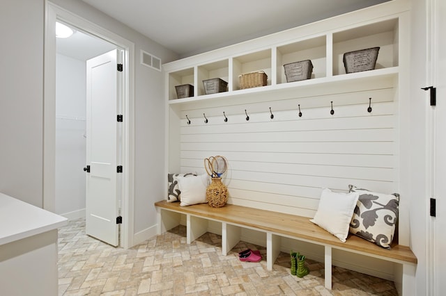 mudroom featuring brick floor, visible vents, and baseboards