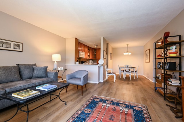 living room featuring a notable chandelier, wood finished floors, and baseboards