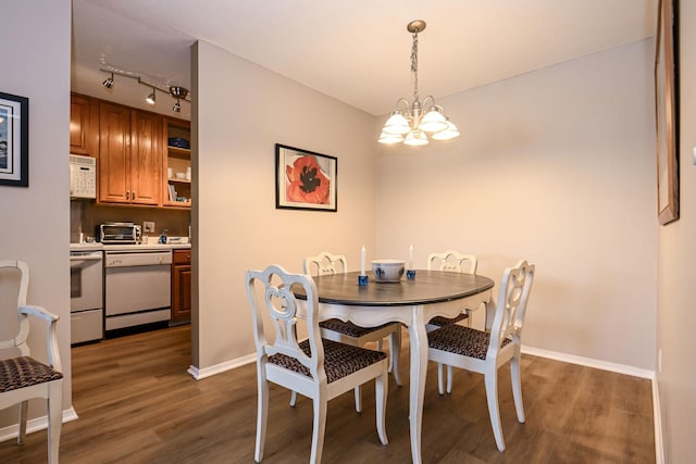 dining area featuring a toaster, baseboards, dark wood-type flooring, an inviting chandelier, and track lighting