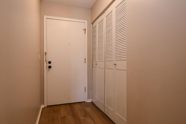 doorway featuring baseboards and wood finished floors