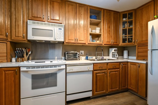 kitchen featuring brown cabinetry, white appliances, light countertops, and a sink