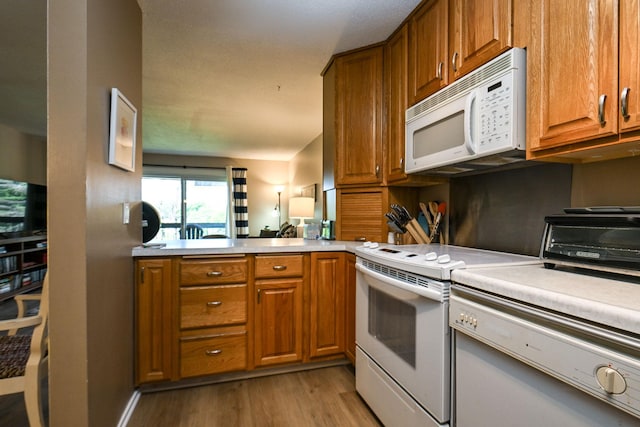 kitchen featuring light wood-style floors, light countertops, white appliances, and brown cabinets