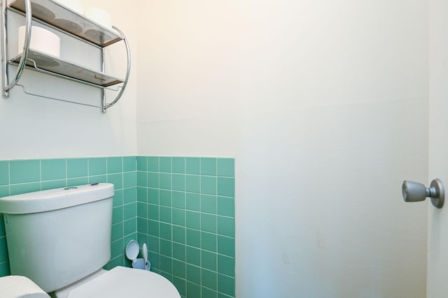 bathroom featuring toilet, a wainscoted wall, and tile walls