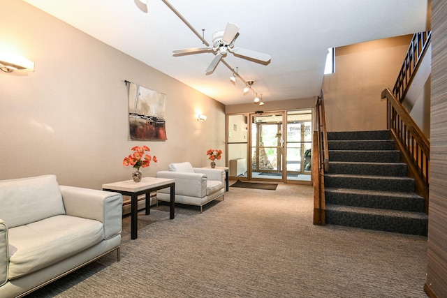 carpeted living room with a ceiling fan and stairway