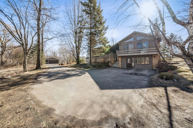 view of front facade with aphalt driveway, brick siding, and a balcony