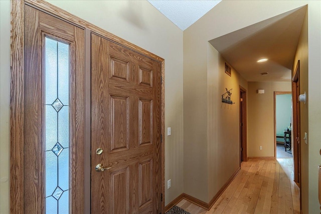 hall featuring light wood-style flooring, visible vents, and baseboards