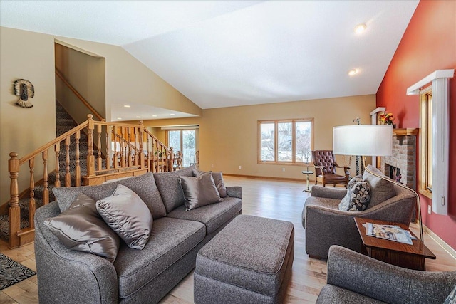 living room with light wood-type flooring, a fireplace, stairway, and a wealth of natural light