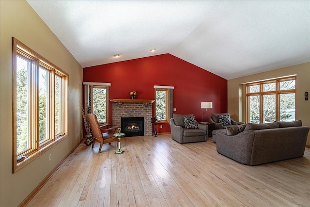 living area with a brick fireplace, vaulted ceiling, light wood-style flooring, and baseboards