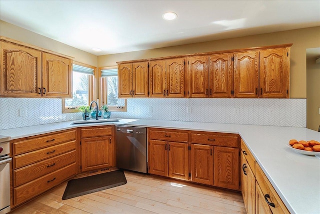 kitchen featuring light wood finished floors, brown cabinets, light countertops, stainless steel dishwasher, and a sink