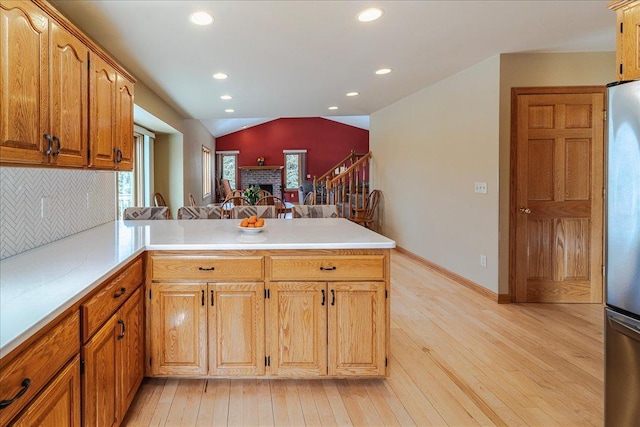 kitchen with lofted ceiling, freestanding refrigerator, a healthy amount of sunlight, and a peninsula