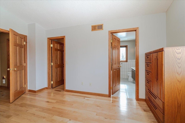 unfurnished bedroom featuring visible vents, light wood-style flooring, and a textured ceiling