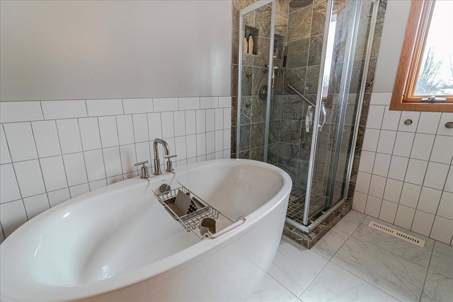 bathroom with tile walls, visible vents, a freestanding bath, and a shower stall