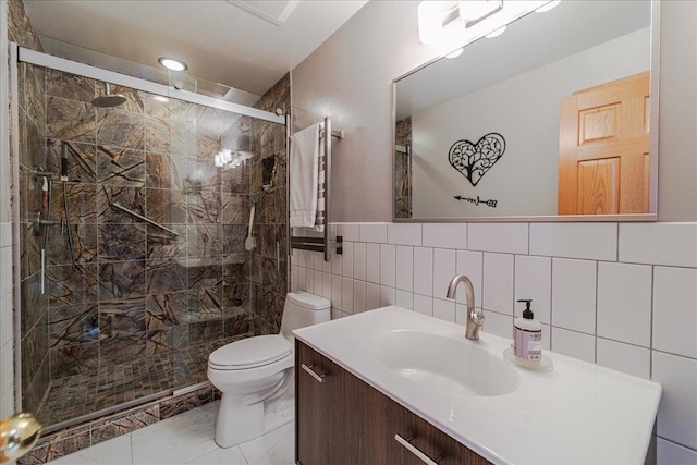 bathroom with vanity, a shower stall, toilet, and tile walls