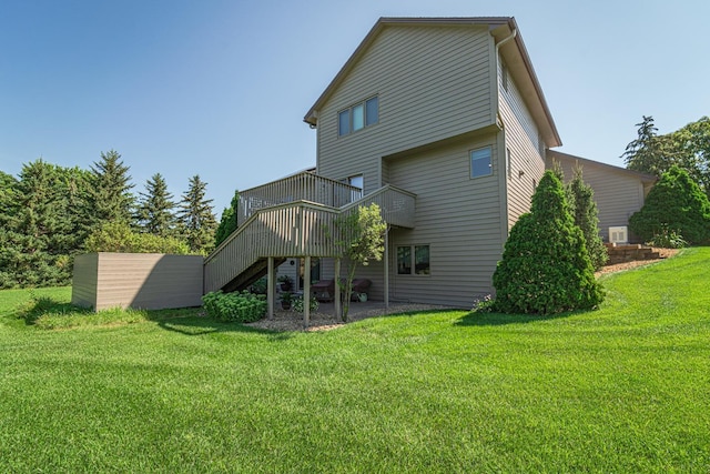 rear view of property featuring a lawn, a wooden deck, and stairs